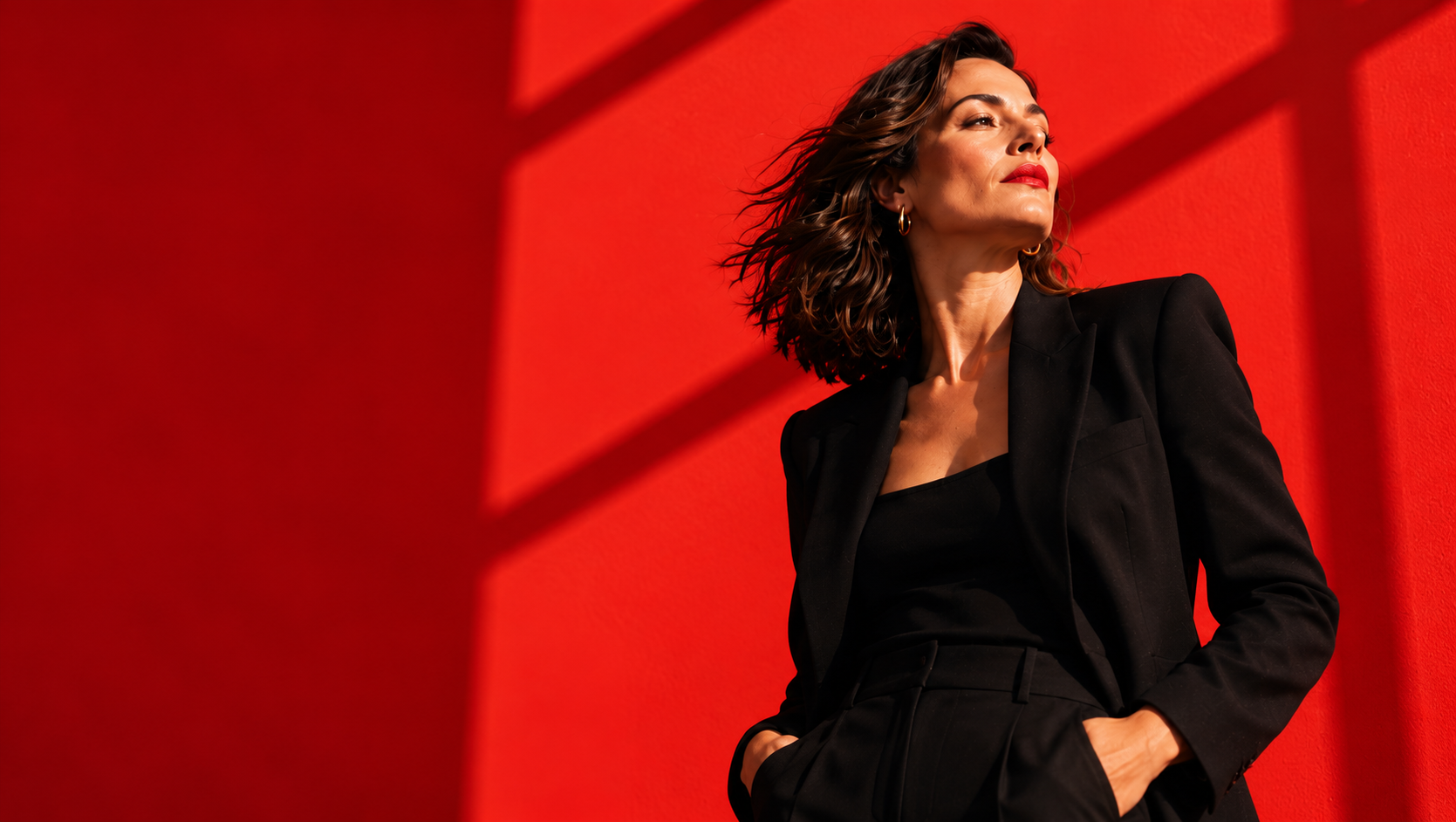 Mikaela Jackson, career coach and founder of She Almighty, in a black suit against a red wall